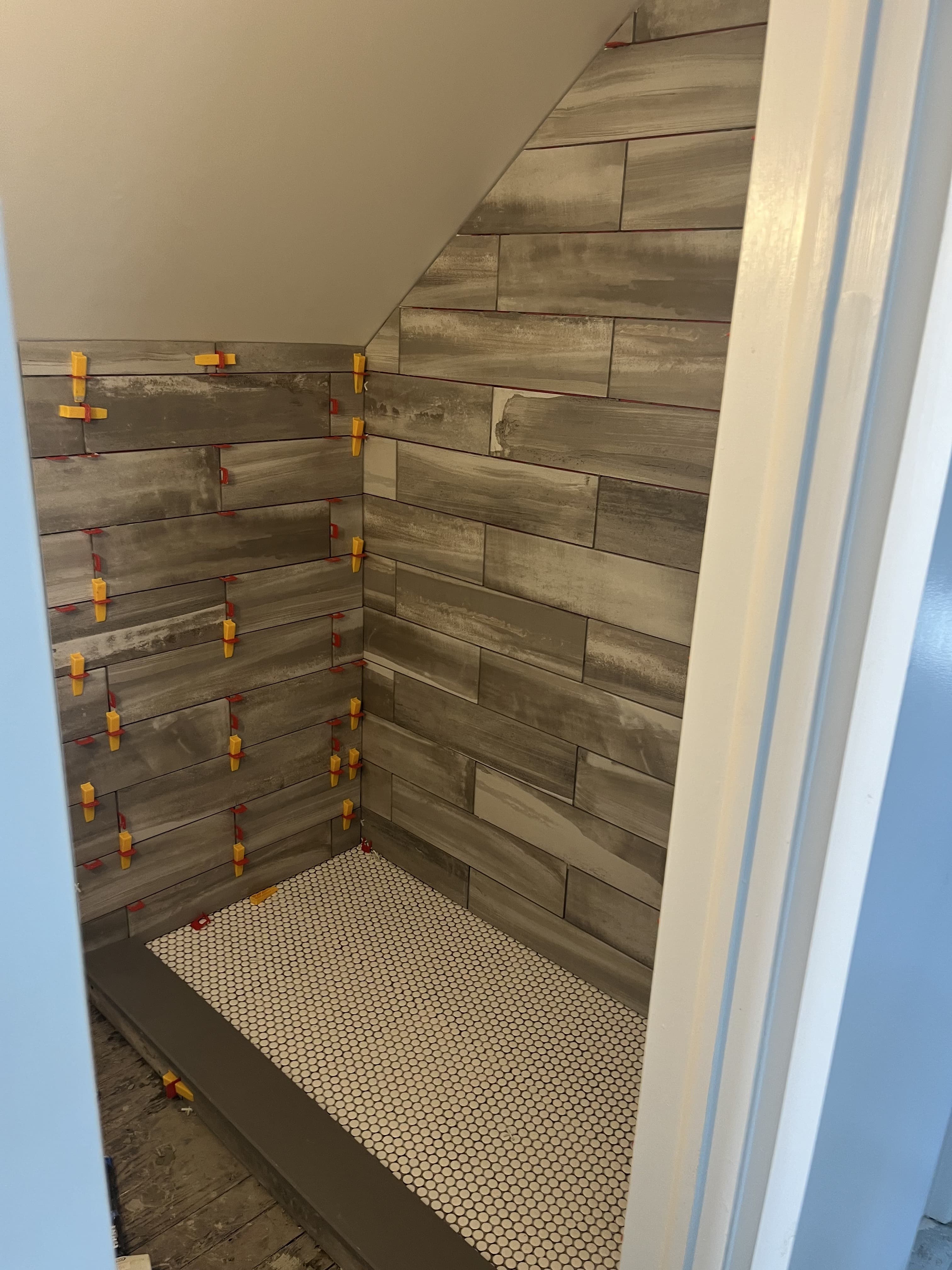 Shower tile installation in progress with wall tile and shower base visible.