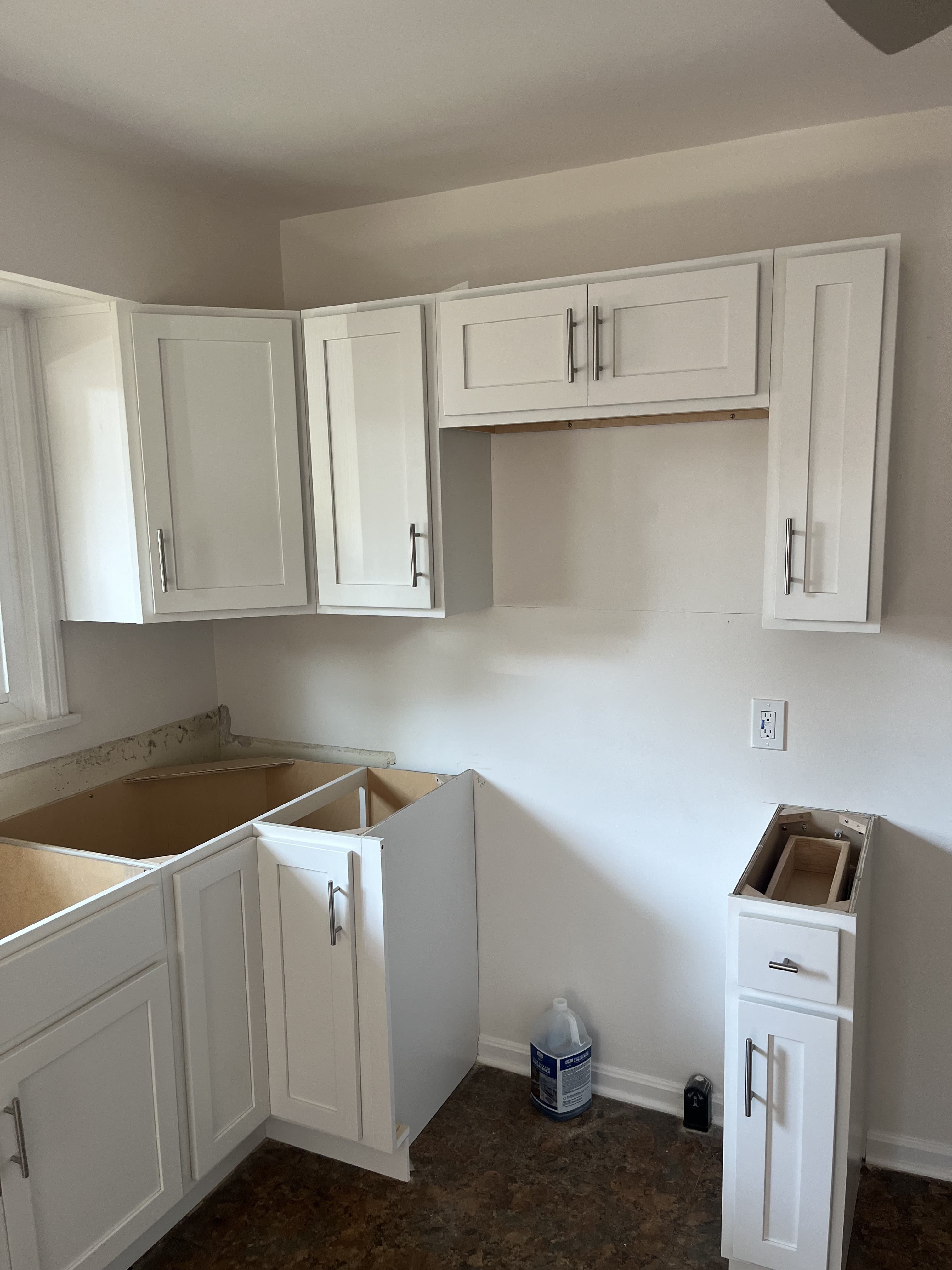 Kitchen cabinet installation in progress with white shaker-style cabinets.