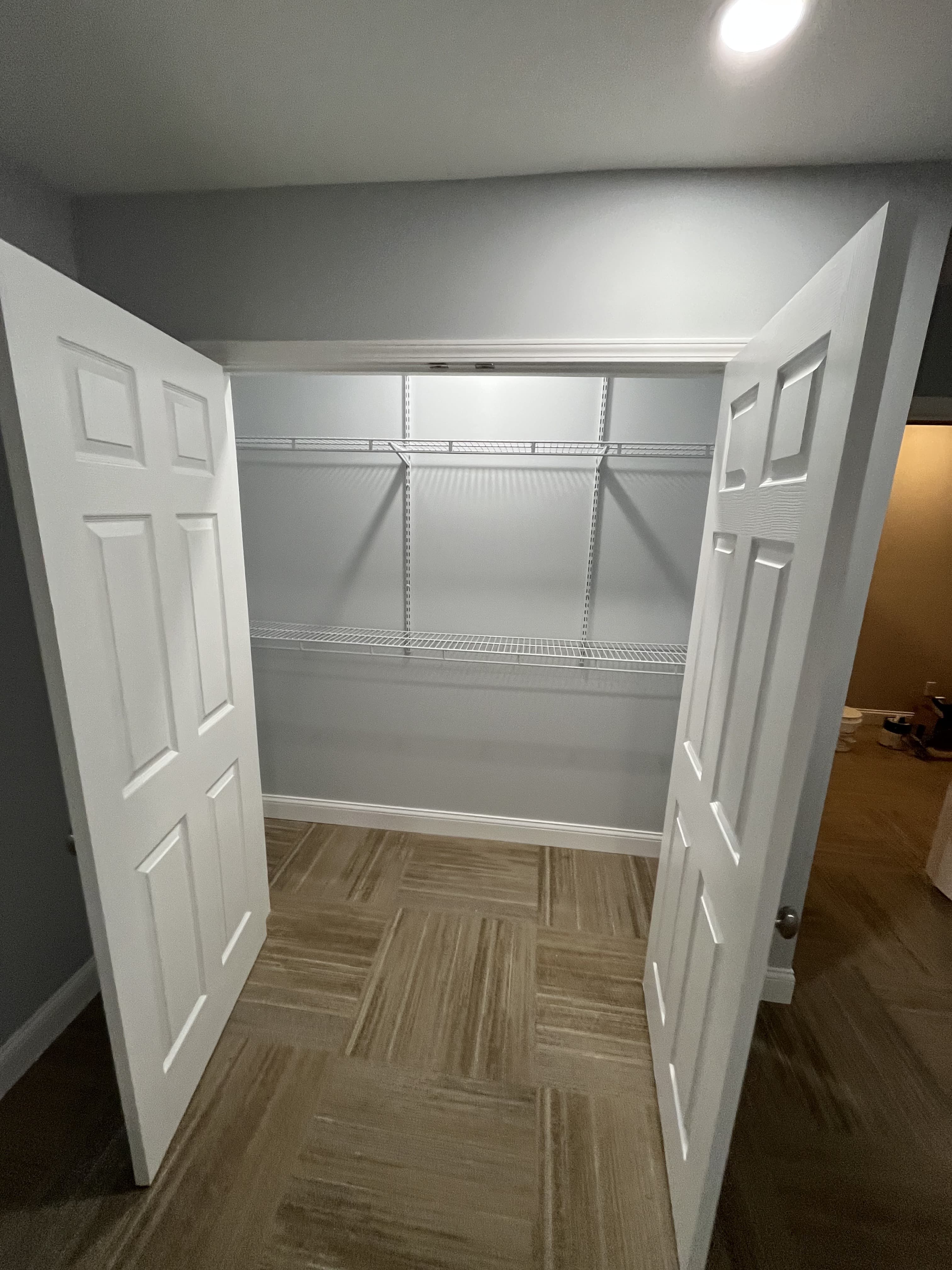Finished closet area with shelving and double doors.