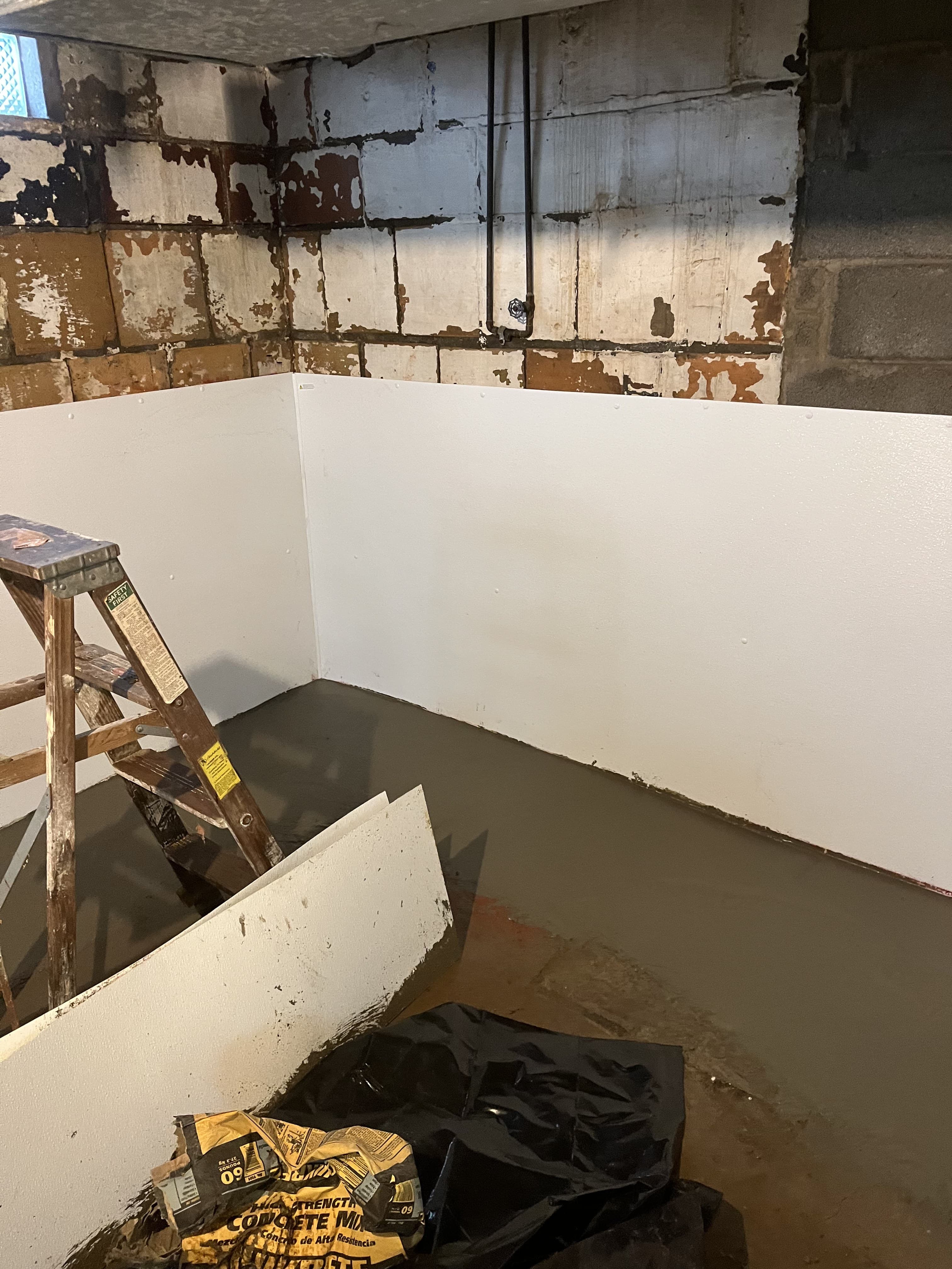 Freshly poured concrete section in a basement repair area.