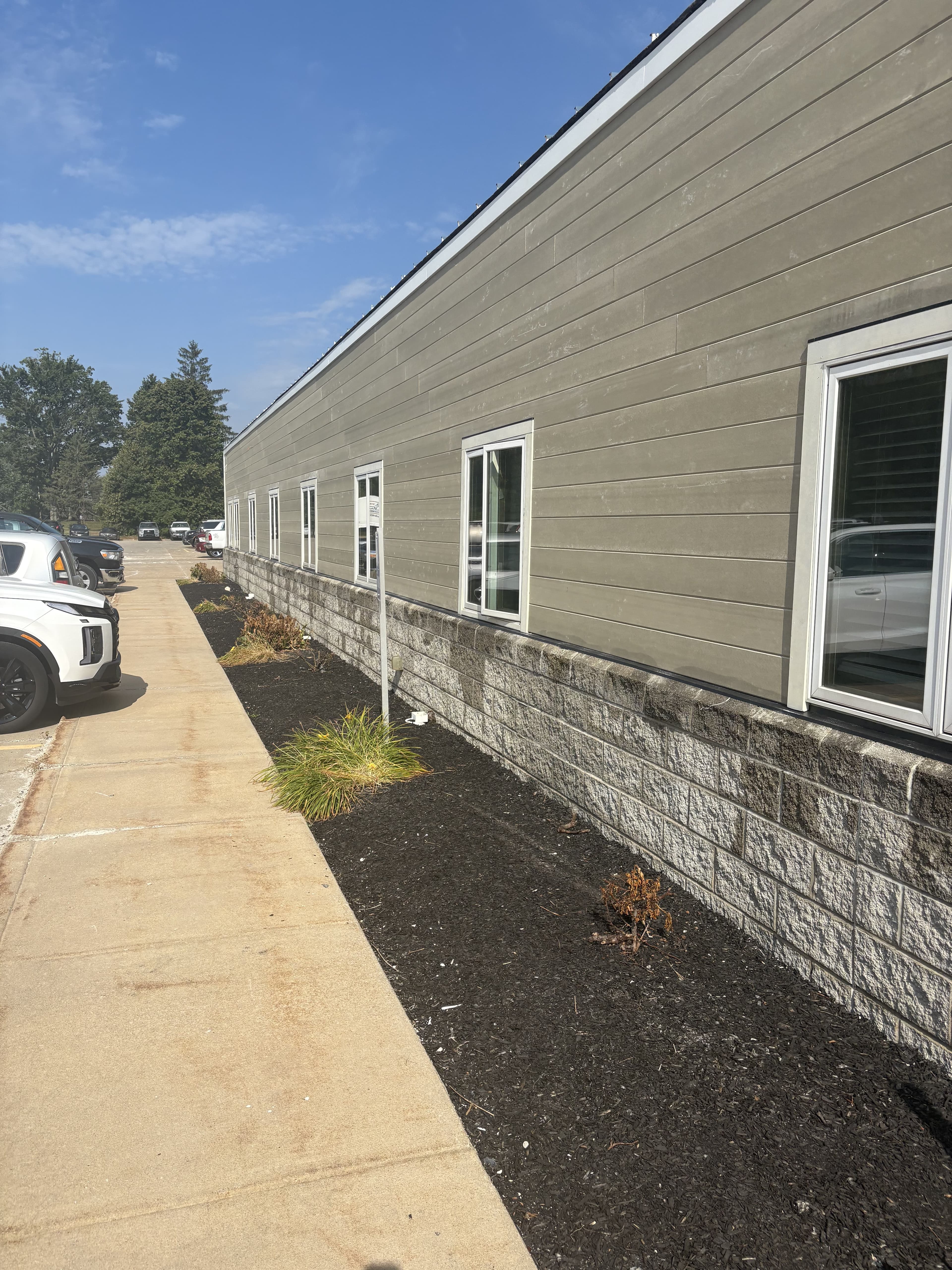 Finished exterior corner with siding, stone base, and landscaping.