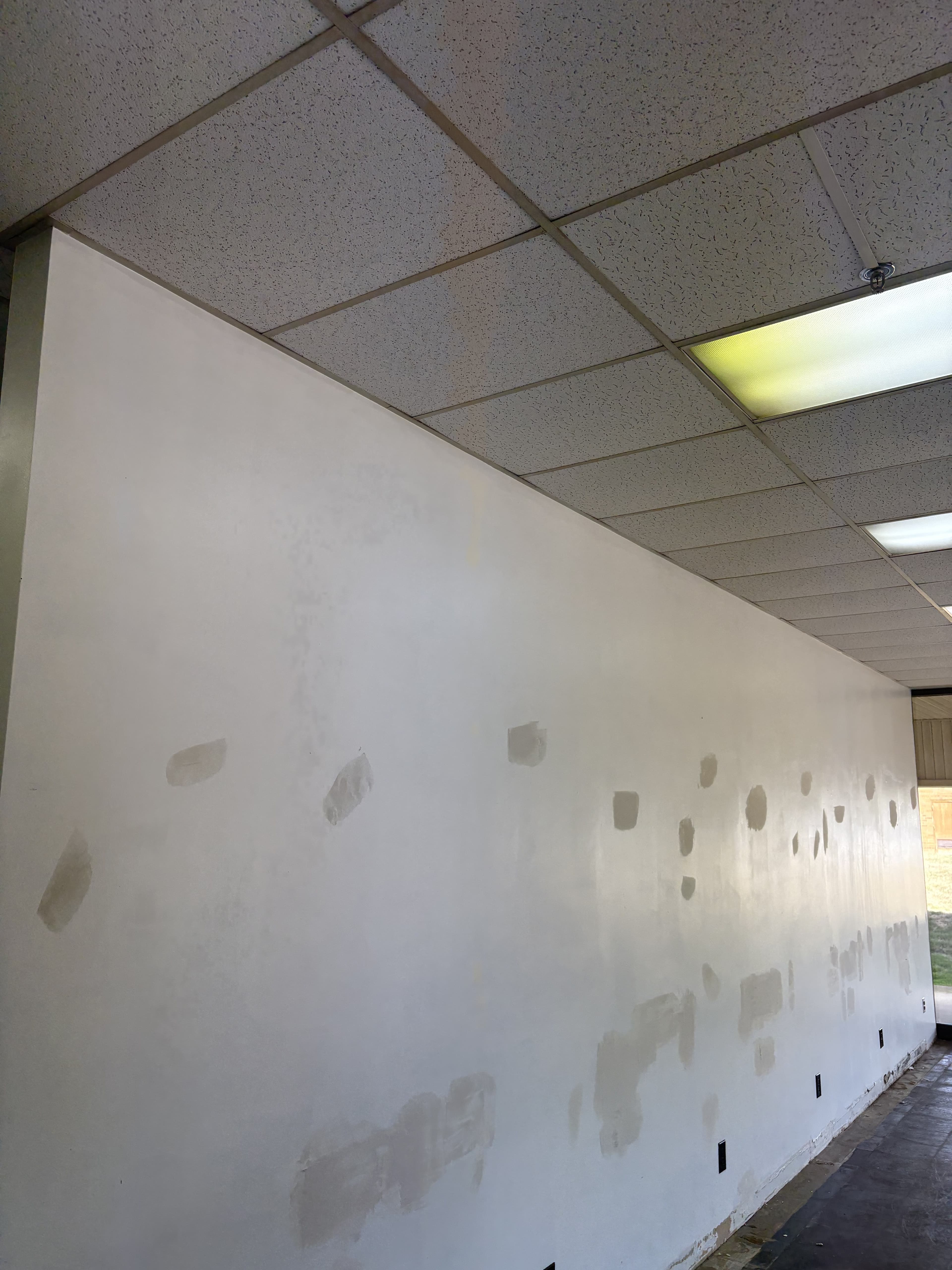 Commercial wall with exposed patches and prep work underway.