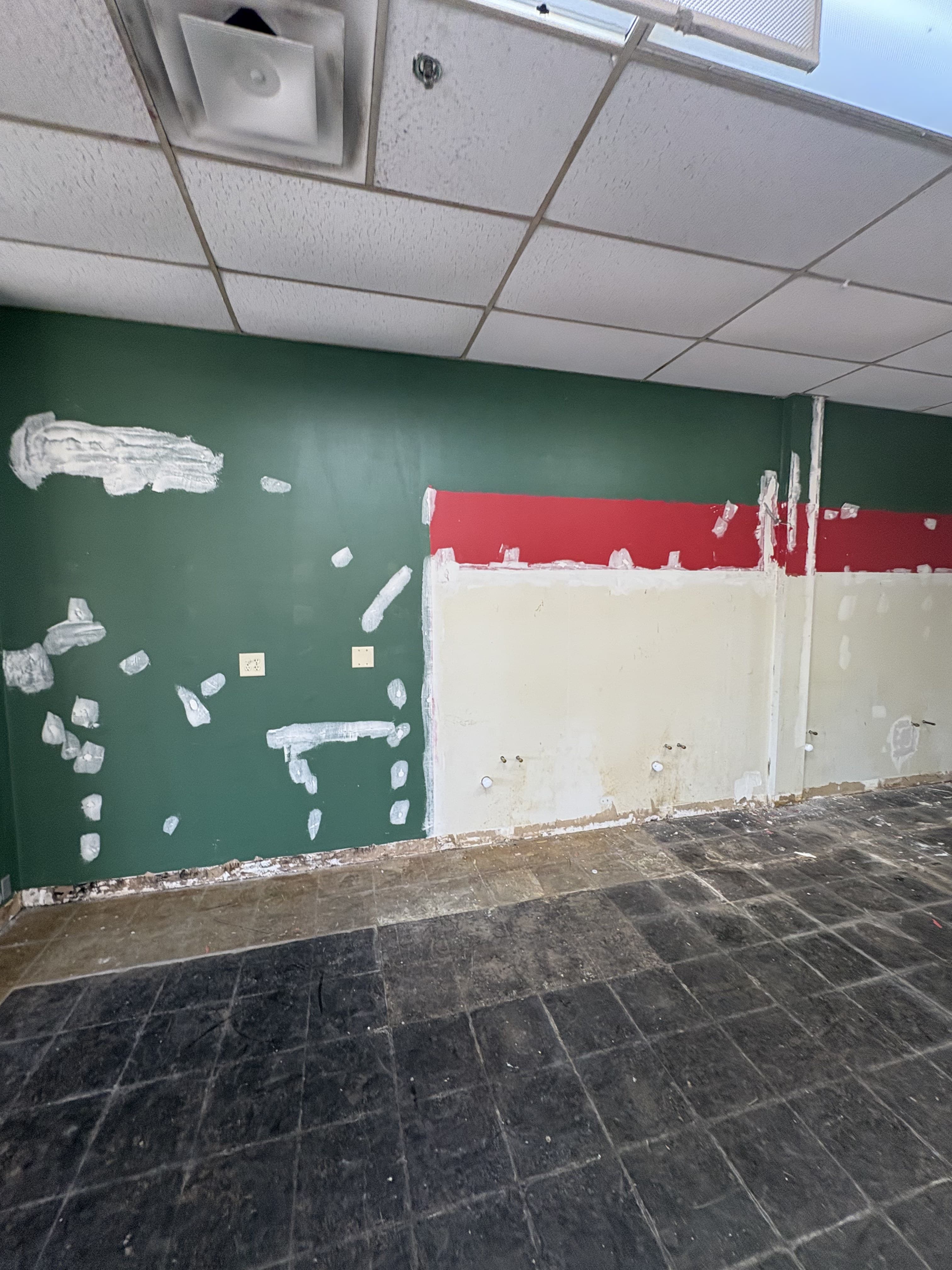 Commercial wall under repair with patching and surface prep before final finishing.