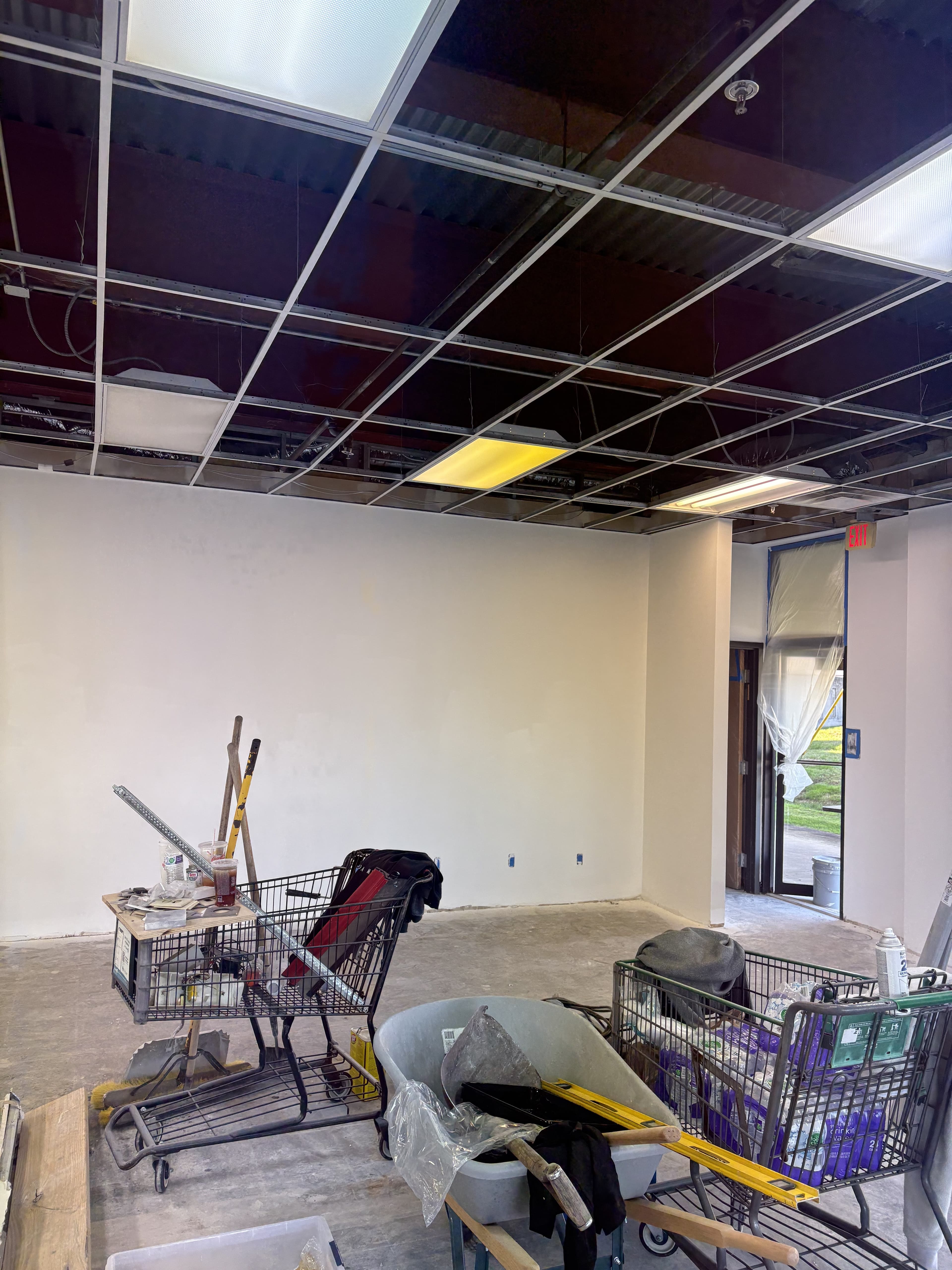 Commercial room with ceiling grid removed during build-out.