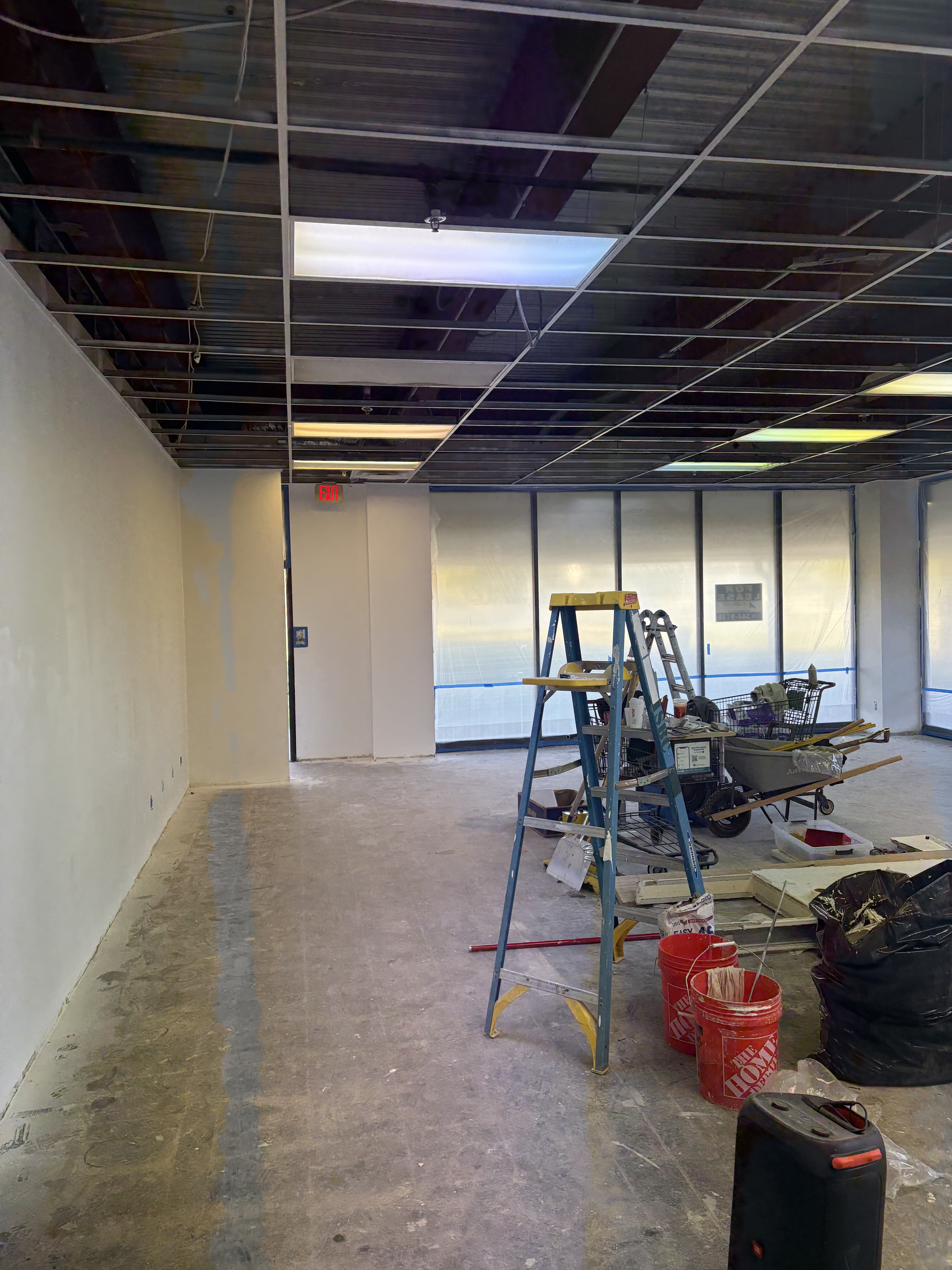 Commercial build-out space with glass frontage and open ceiling.