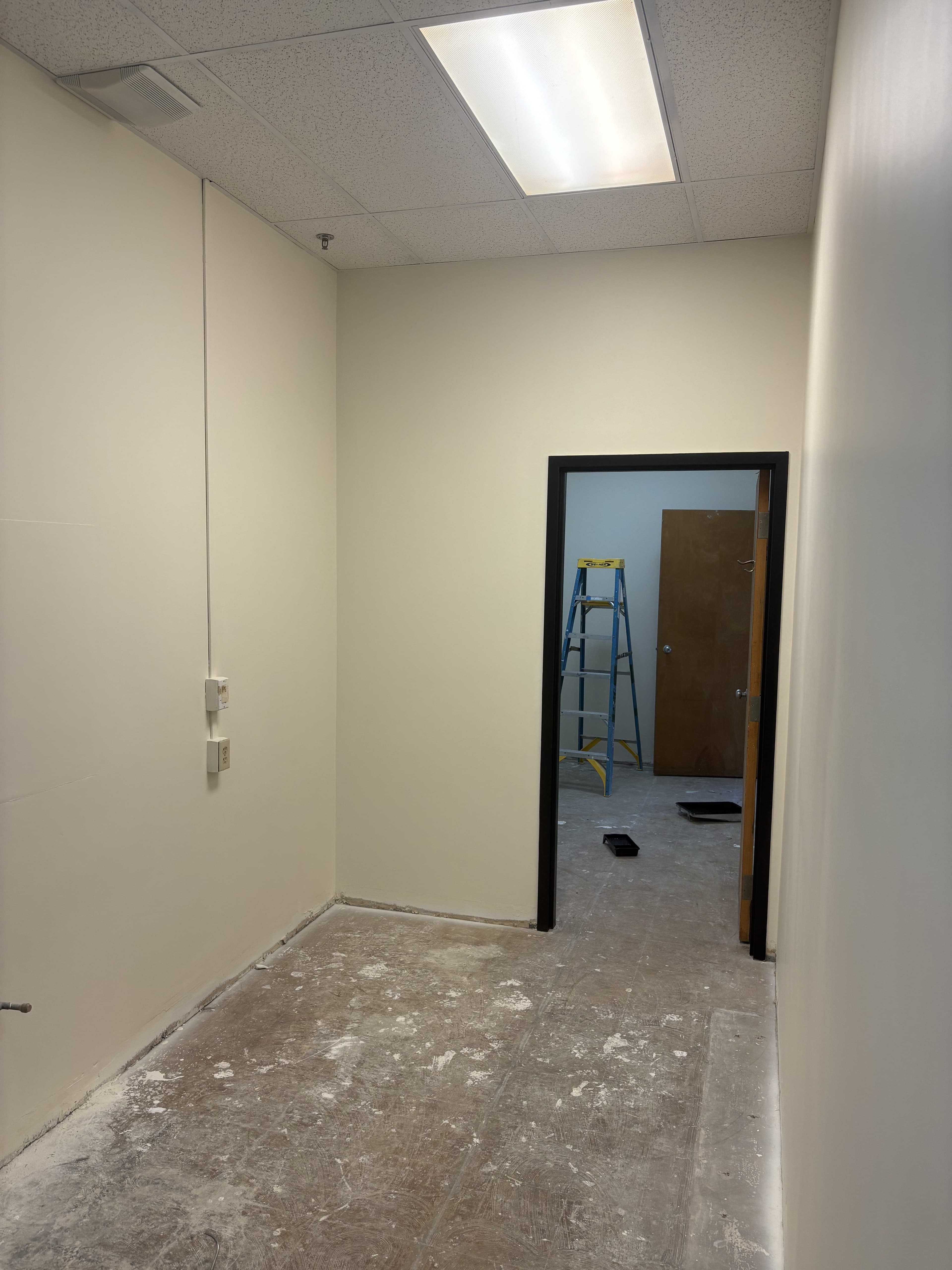 Commercial hallway with finished paint and door trim before final flooring is installed.