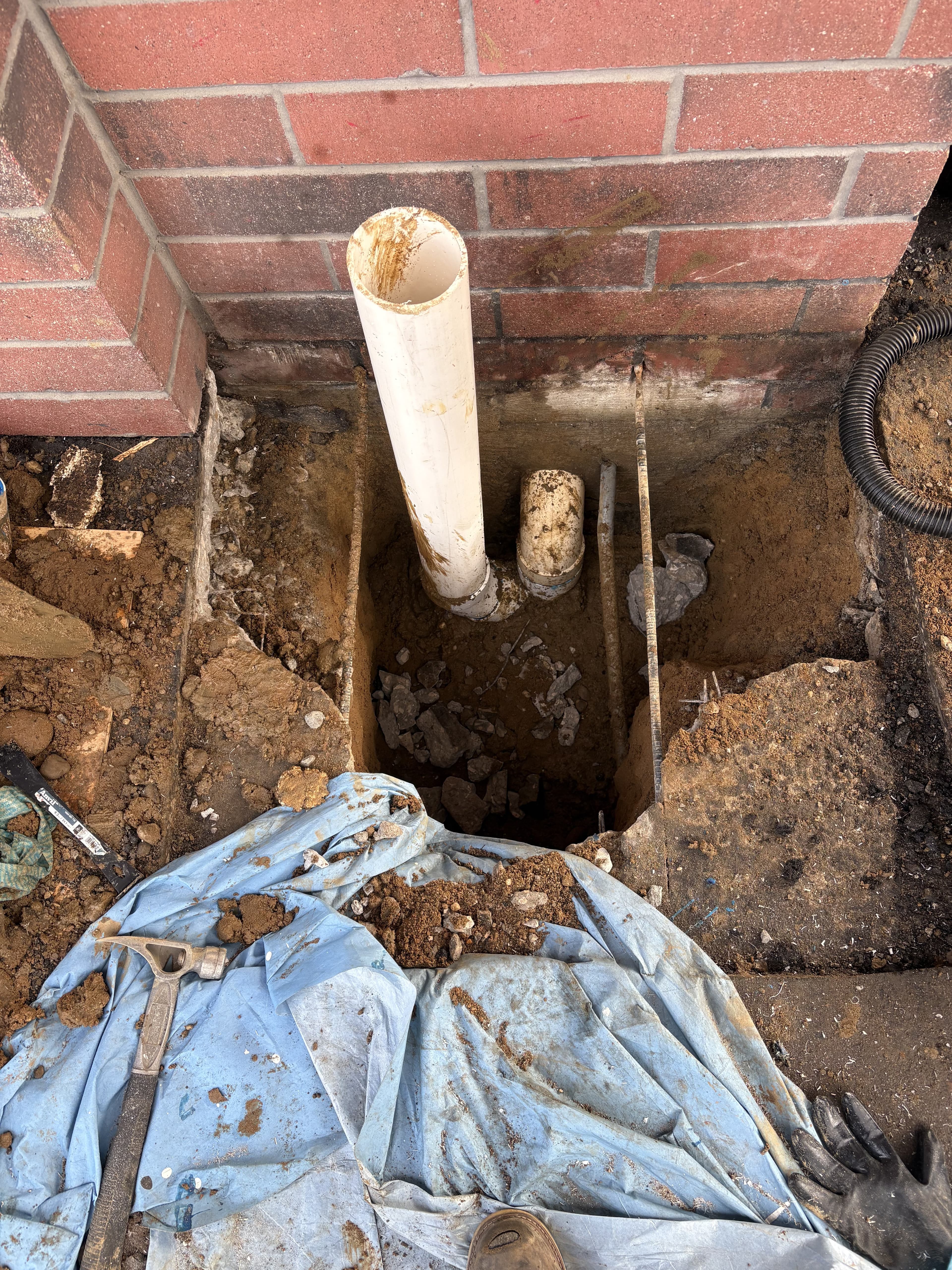 Wider drainage excavation view during repair work.