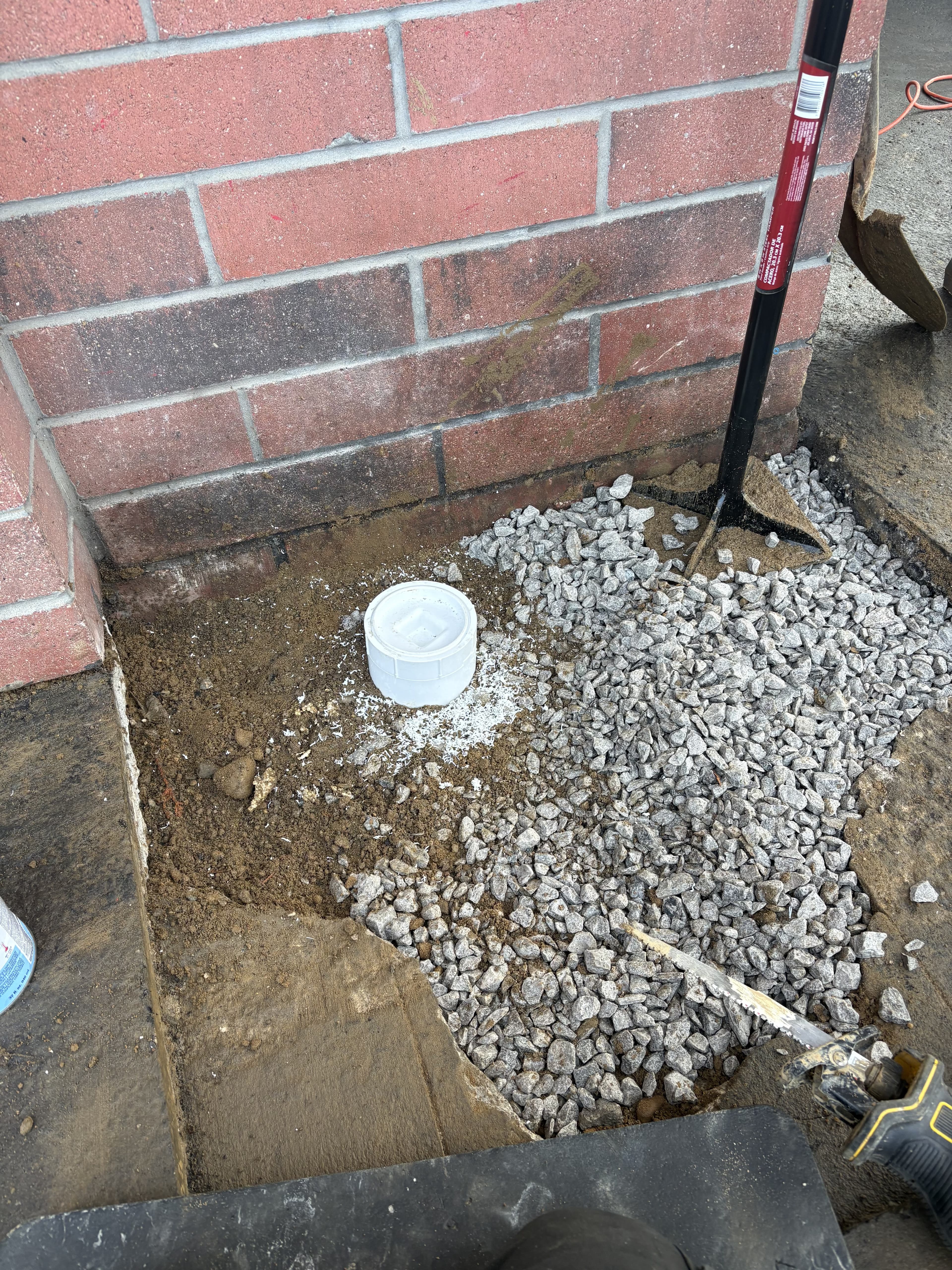 Drainage repair area with gravel base before final patch.